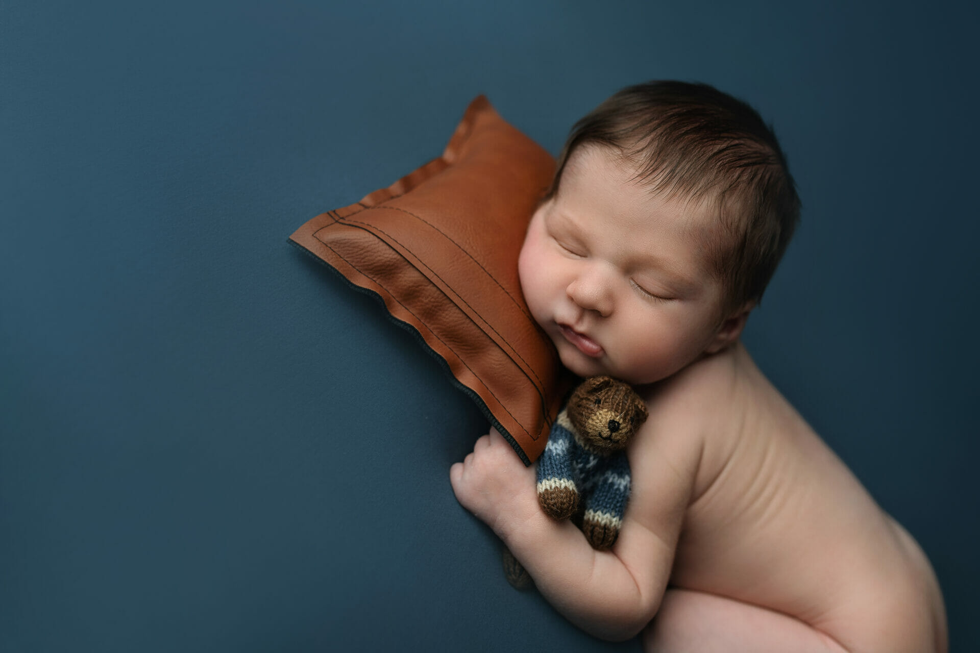 newborn baby boy snuggling teddy bear in Lafayette LA portrait studio