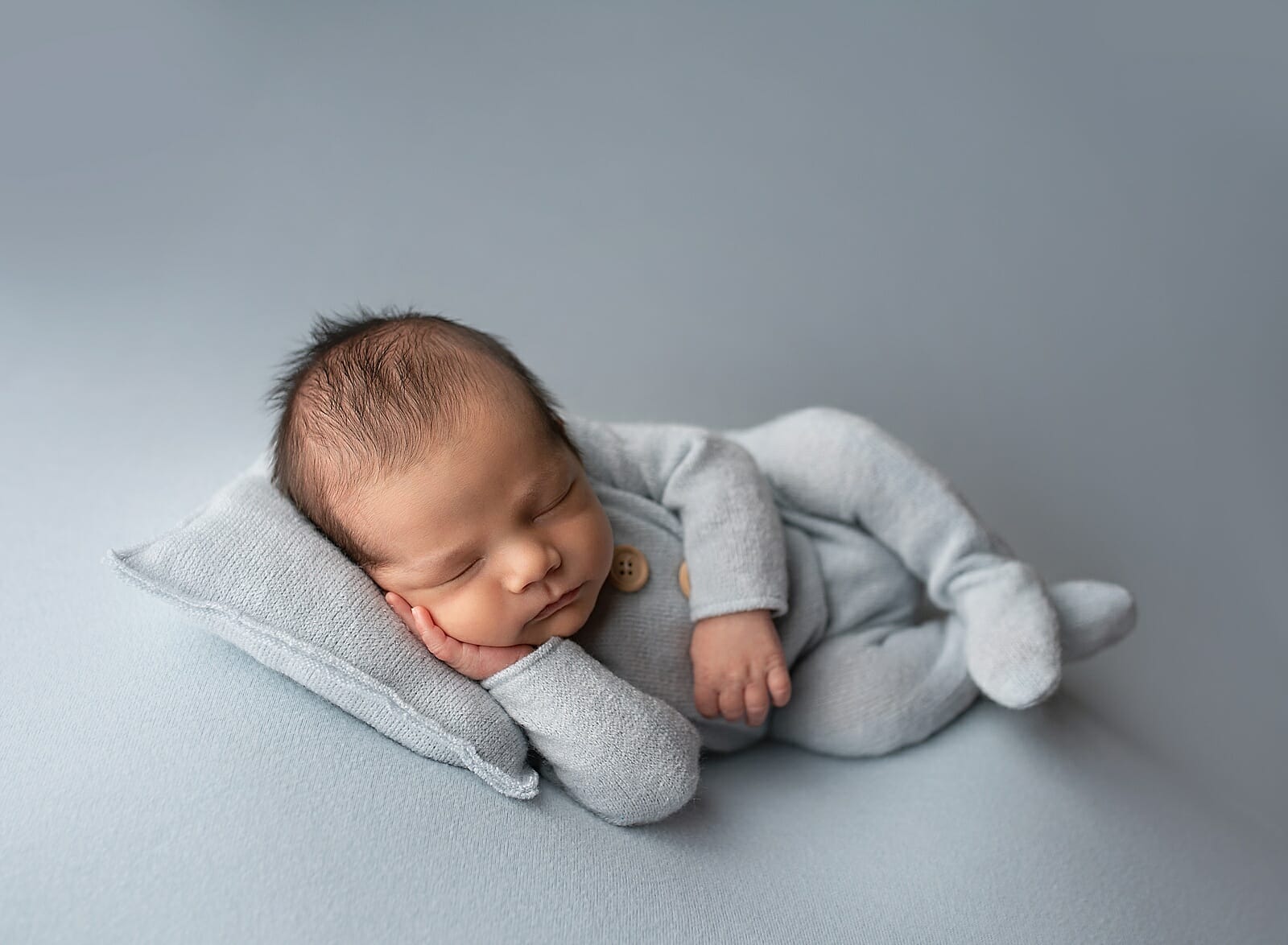 A newborn poses on a blue backdrop for a Lafayette LA photographer.