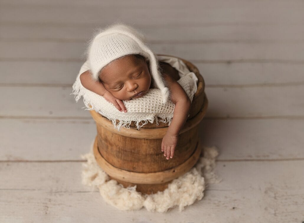Newborn photography shows a baby posed in a basket in Lafayette LA.