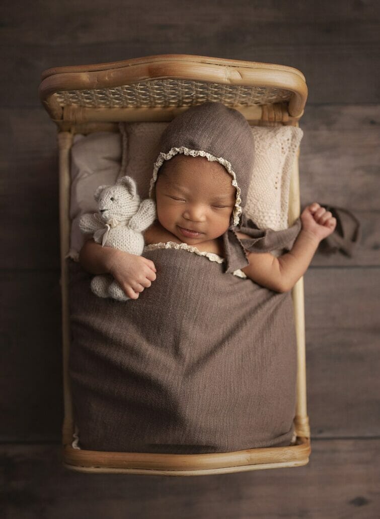 A Lafayette LA photographer photographs a newborn baby in a crib.