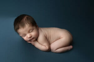 A snuggling baby boy on blue blanket with name spelled out at New Orleans LA photography studio.