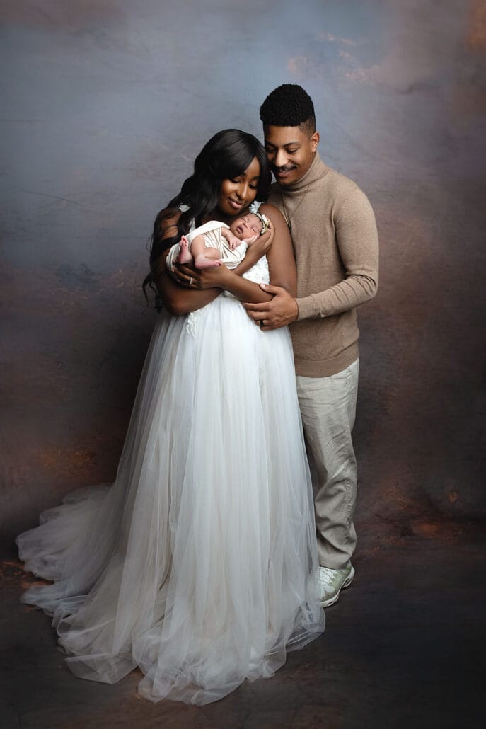 New mom and dad with their baby girl cuddling, looking at baby smiling with New Orleans childbirth class.