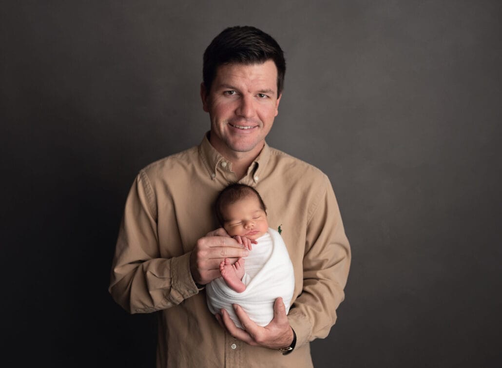 Dad holding newborn baby boy in studio.
