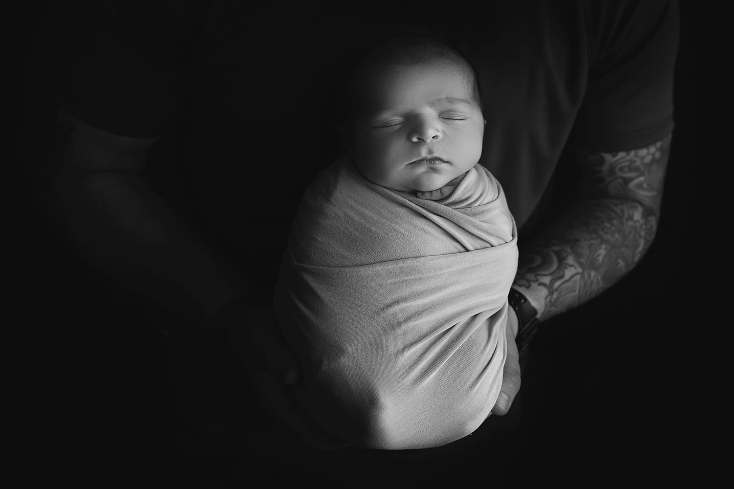 New father holding newborn baby boy swaddled at Baton Rouge's top fertility clinic.