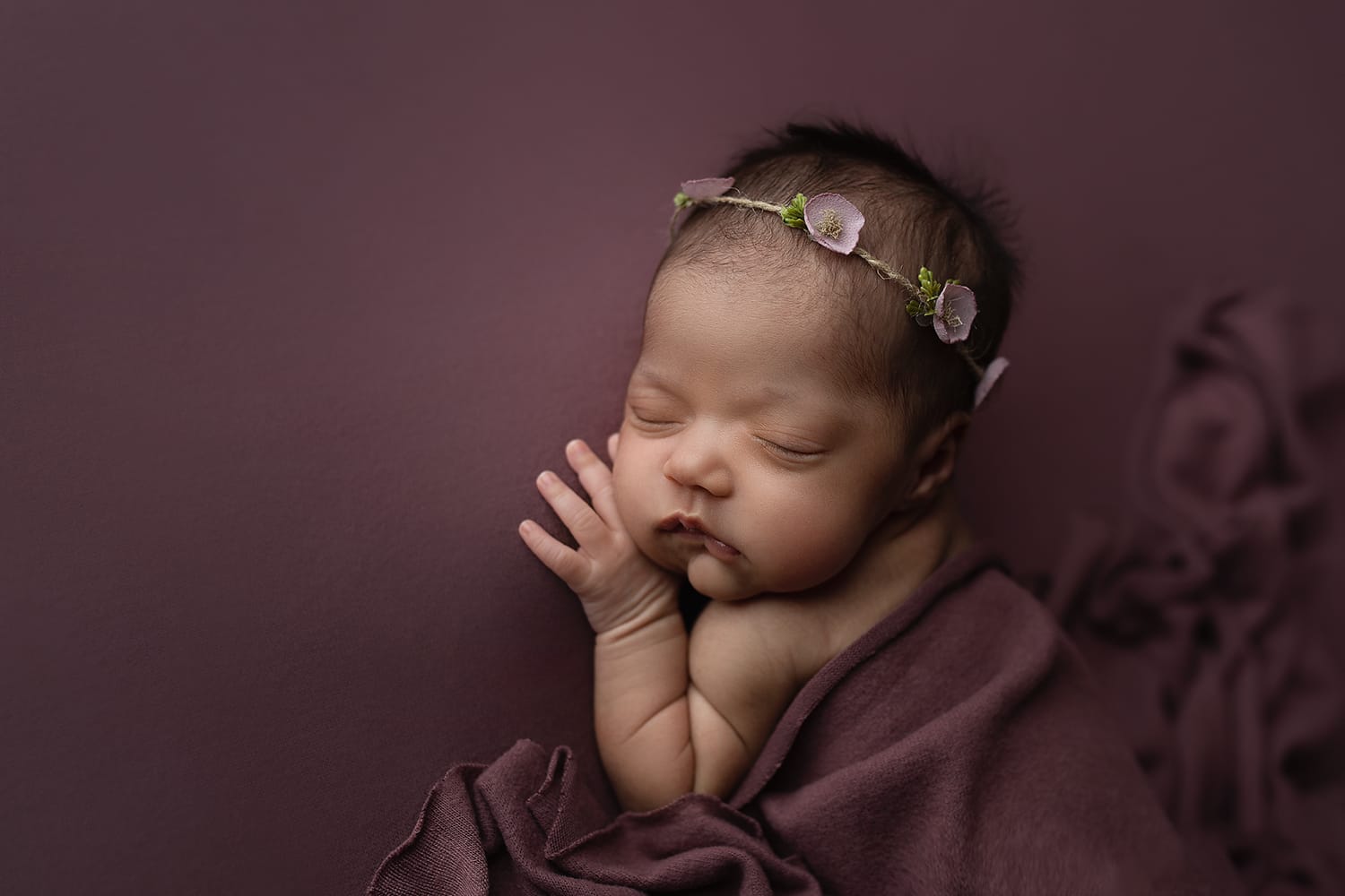 Baby girl lying on tummy with hand under cheek with floral headband at Baton Rouge doula.