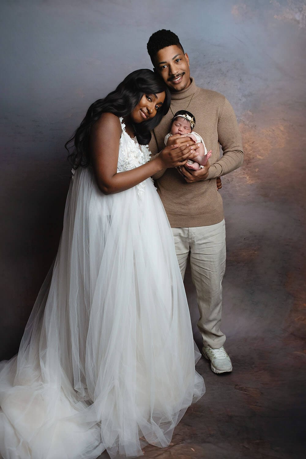 A new mom and dad with their newborn in the studio for a newborn photo session.