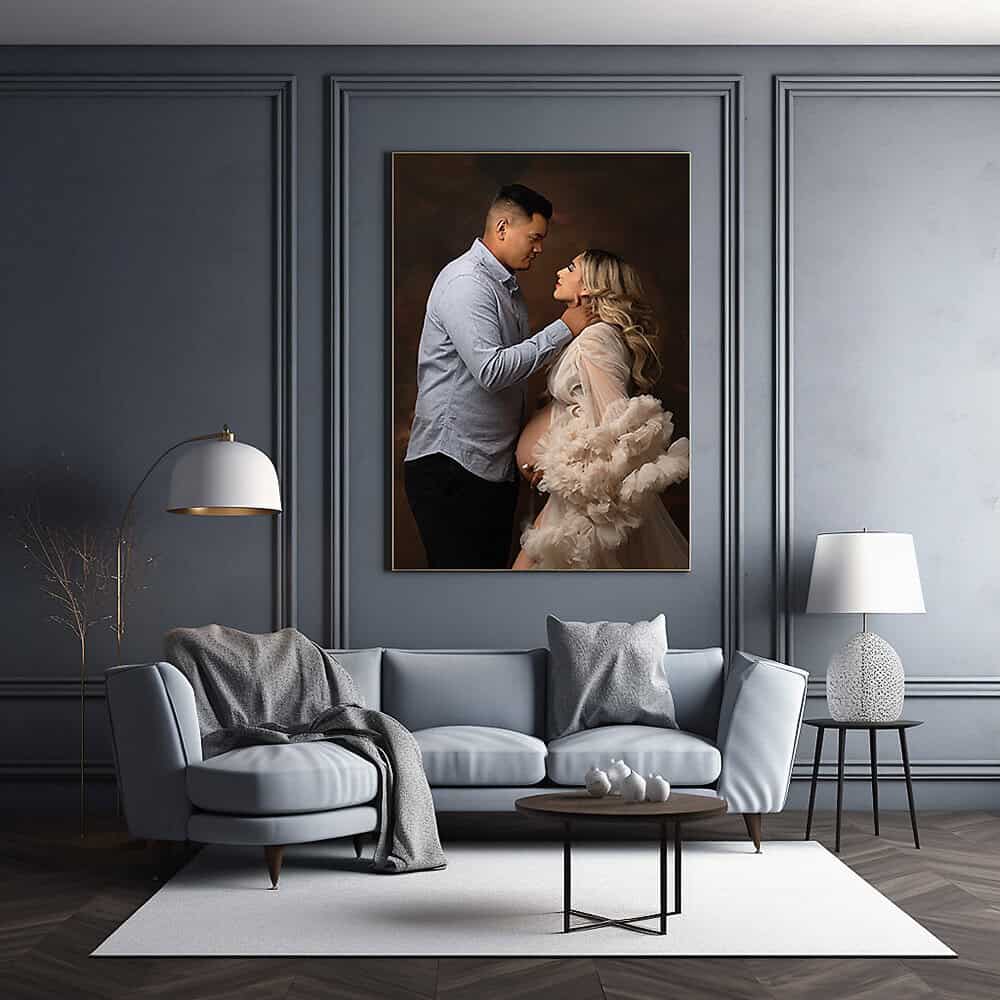 A stylish living room with a light blue sofa, matching chairs, a floor lamp, and a coffee table. A large portrait of a couple, with the woman in a flowing dress, hangs on the dark gray paneled wall above the sofa. Melinda Gilmore Photography - Maternity & Newborn Photographer - Louisiana