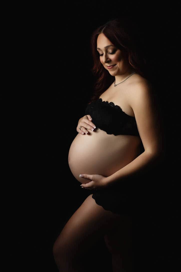Pregnant woman in black lingerie holding belly